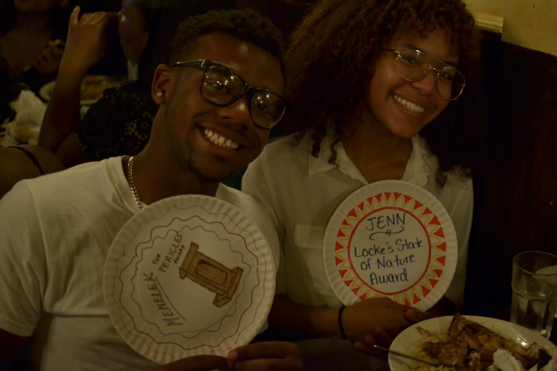 Image of Jennifer Jiminian (right) and another student receiving her paper plate award, the "Locke's State of Nature" award, at the end of the Freedom and Citizenship program.