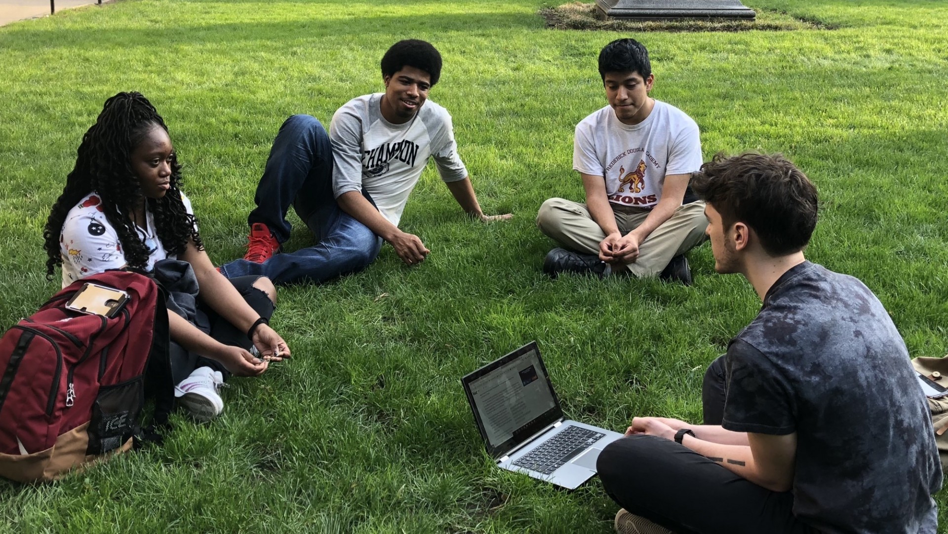 Four students sitting on the grass, talking